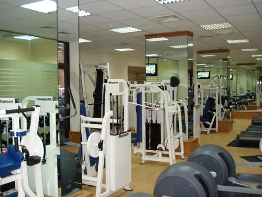 Gym floor with weight machines under a suspended ceiling of recessed lights and air-conditioning diffusers